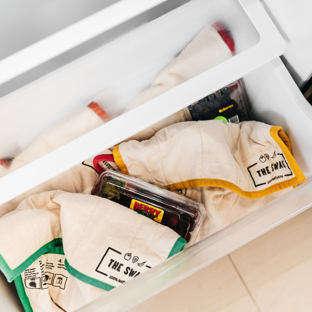 
                      
                        The Swag dampened reusable produce bags sitting in the crisper of the fridge with punnets of berries nestled in around them - The Swag AU
                      
                    