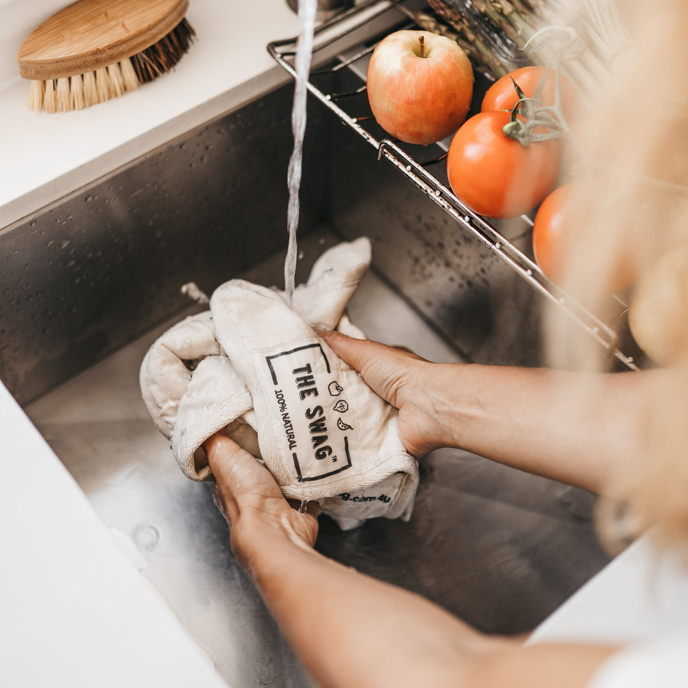 
                      
                        The Swag reusable produce bag for the fridge with a natural trim being scrunched up and dampened down under the tap  - The Swag AU
                      
                    