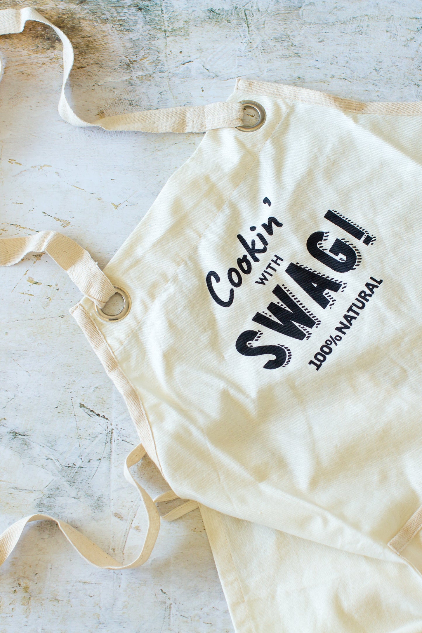 A gorgeous, beautifully hand made Swag apron made from unbleached unseeded cotton and featuring the slogan "Cookin' with Swag" - The Swag AU