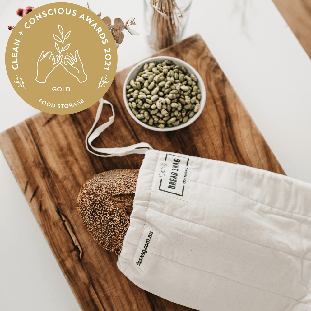 
                      
                        The Swag reusable Bread bag on a wooden bread board with sourdough loaf plus featuring the Clean and Conscious Gold Award banner logo - The Swag AU
                      
                    