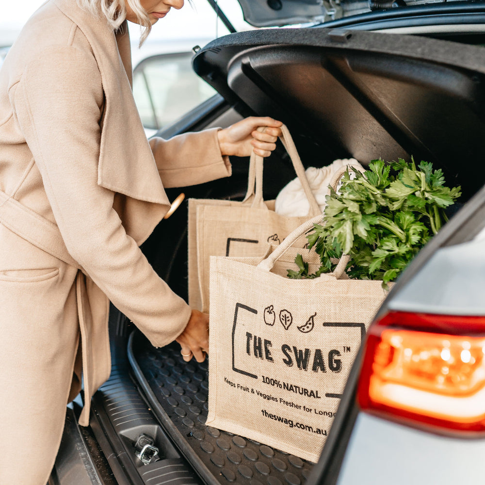 
                      
                        Woman putting The Swag reusable and 100% natural carry bags filled with fresh fruit and veggies into the boot of the car - The Swag AU

                      
                    