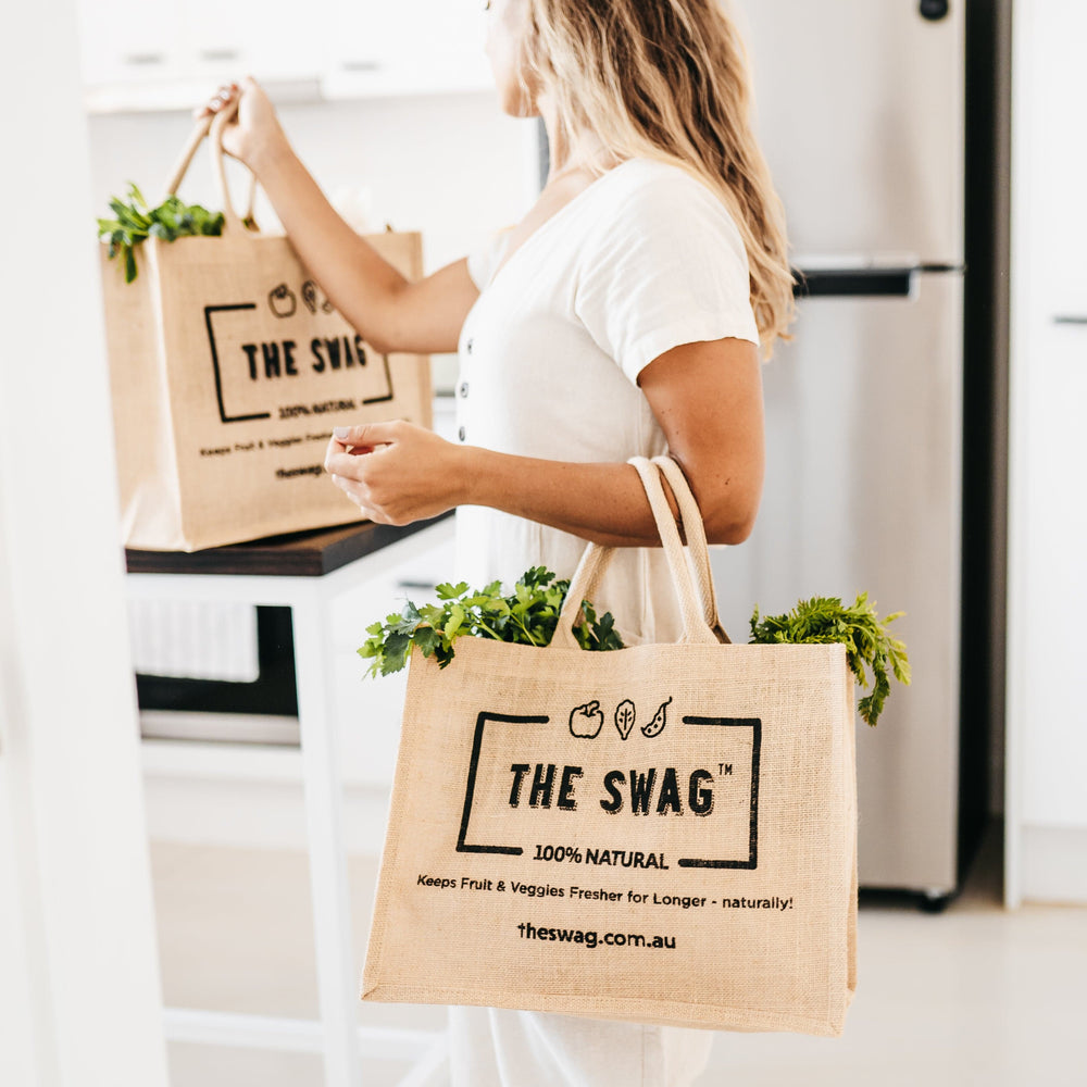 
                      
                        Woman arriving home holding The Swag reusable and 100% natural carry bags made from hessian and filled with fresh fruit and veggies - The Swag AU

                      
                    