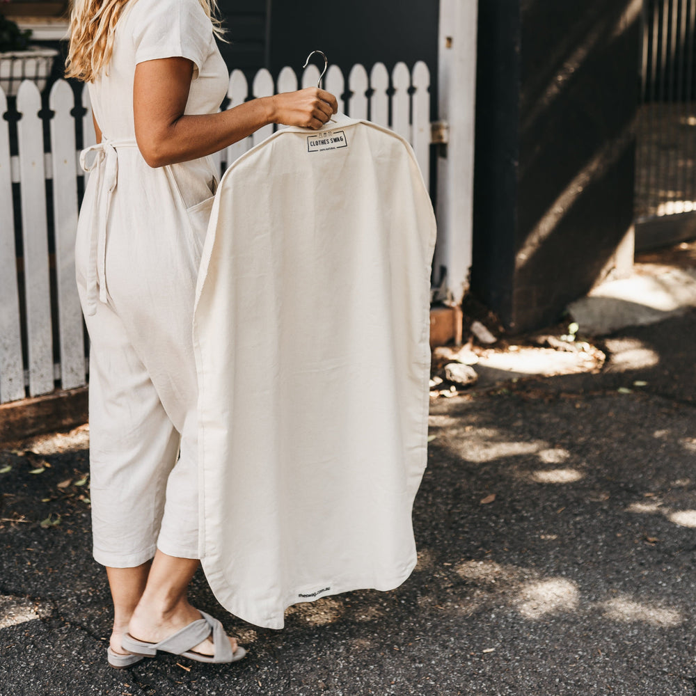 Woman carrying 100% natural and reusable The Clothes Swag filled with clothing on a hanger  - The Swag AU

