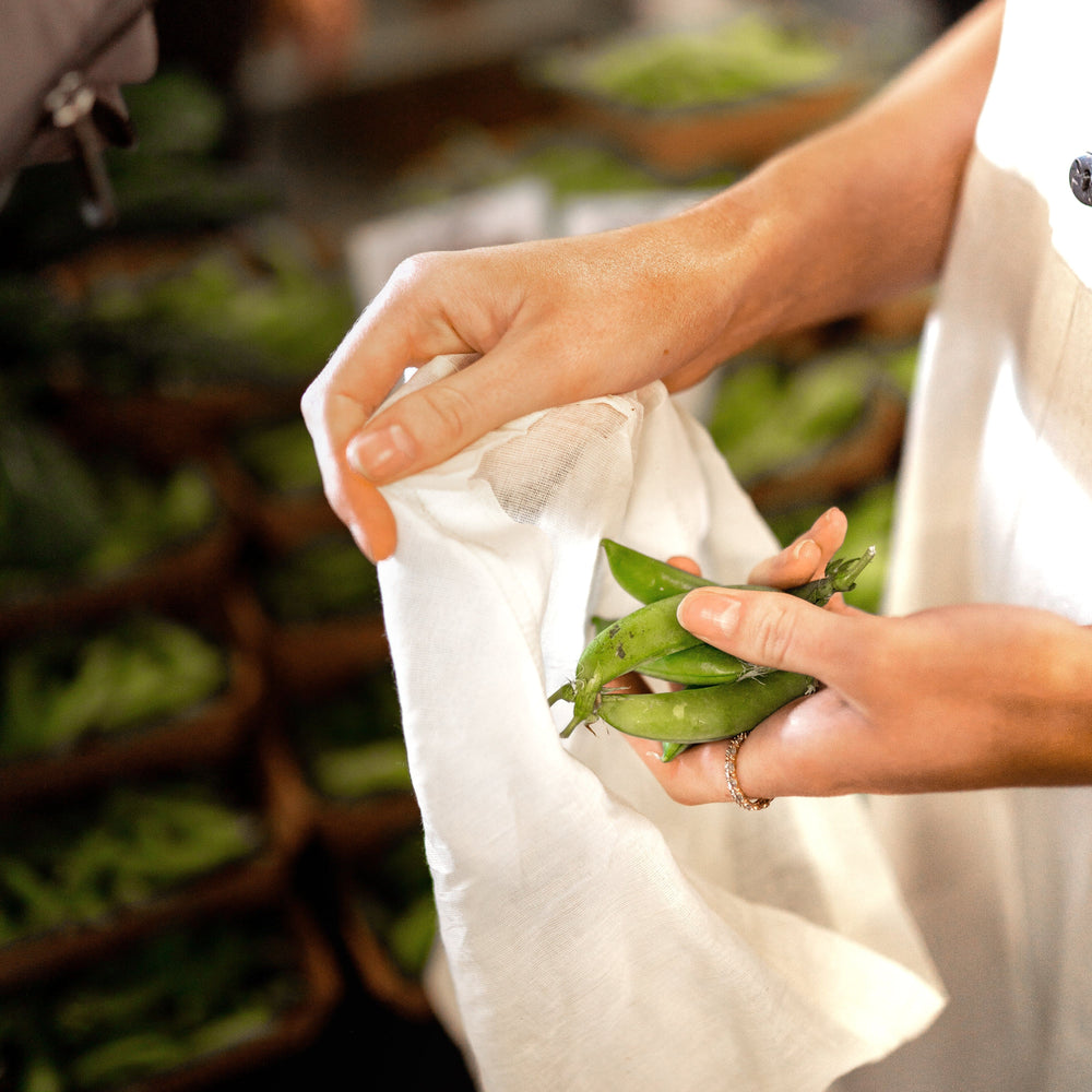 
                      
                        The Swag with a lady at the shops putting snow peas into the lightweight reusable produce bags - The Swag AU
                      
                    